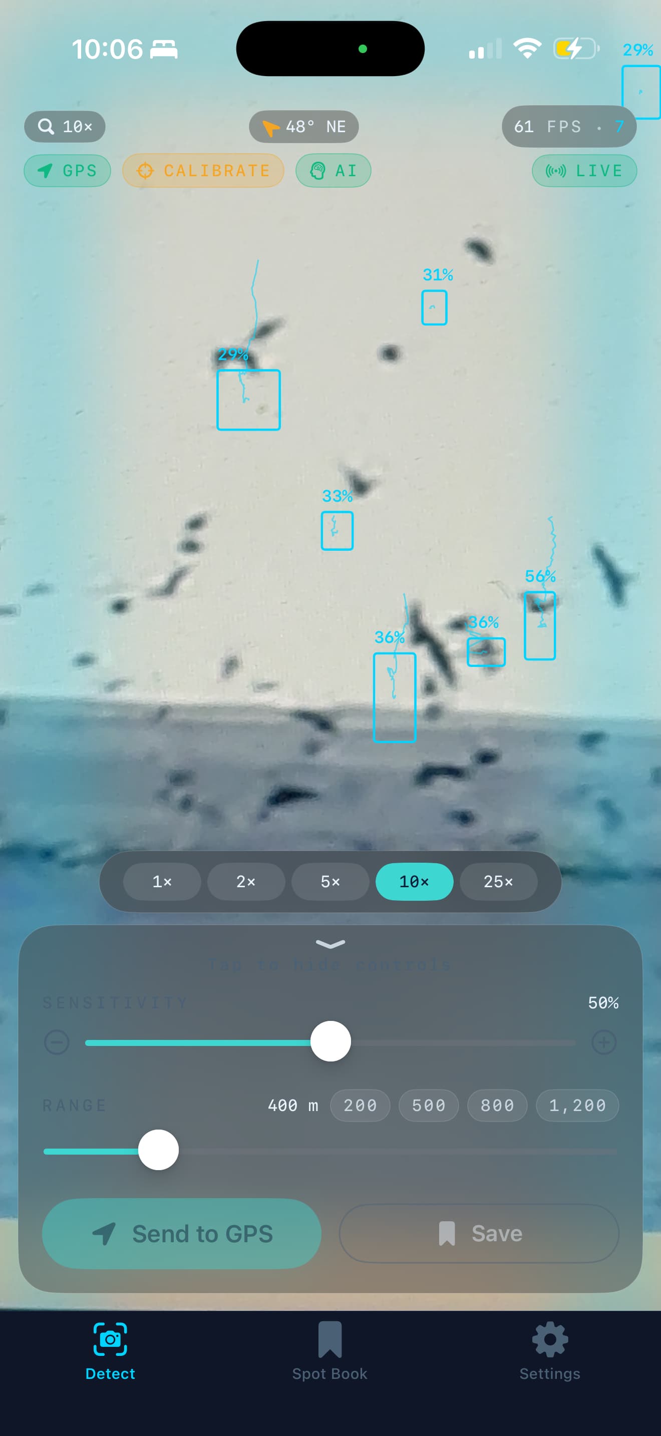 SeaBirds Detect screen on iPhone 16 Pro Max — live camera viewfinder zoomed to 10× over a real horizon, with seven confirmed bird detections bracketed in Sonar Teal bounding boxes and labeled with per-detection confidence scores (24%, 29%, 31%, 33%, 36%, 36%, 56%). Top-bar HUD shows the 10× zoom chip, 48° NE bearing, 61 FPS counter, GPS / Calibrate (amber) / AI status pills, and a LIVE indicator. Bottom sheet shows Sensitivity at 50%, Range at 400 m with one-tap presets at 200 / 500 / 800 / 1200, and the Send to GPS and Save action buttons.